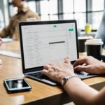 Person Using Macbook Pro on Brown Wooden Desk