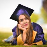 Woman Wearing Purple Graduation Gown Lying on Field