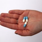 three capsules on person's palm