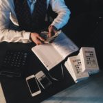 Person Counting Money With Smartphones in Front on Desk