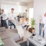 Montage of the same man cleaning a modern open-plan living room and kitchen: vacuuming, dusting, wiping counters, sweeping, and tending a plant.